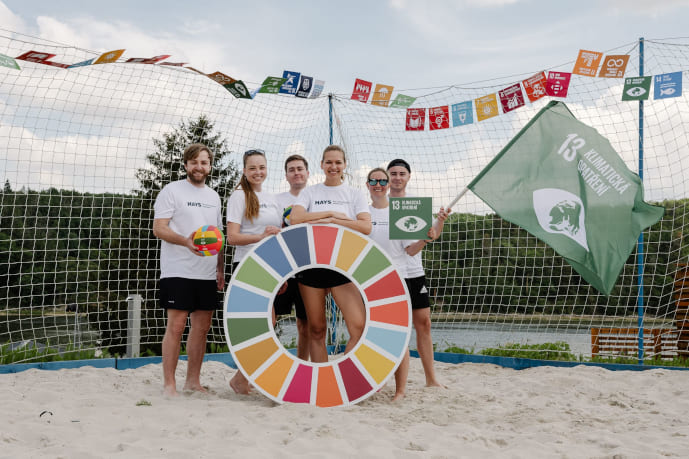 A group of people standing on the beach volleyball court in a charity sports event