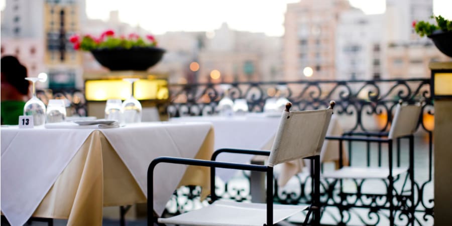 An empty chair at a table in a restaurant on the main square of a town