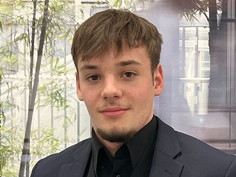 A young man in a black suite smiling